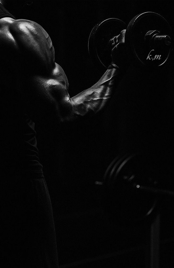 Person lifting weights with a focus on muscles against a dark background
