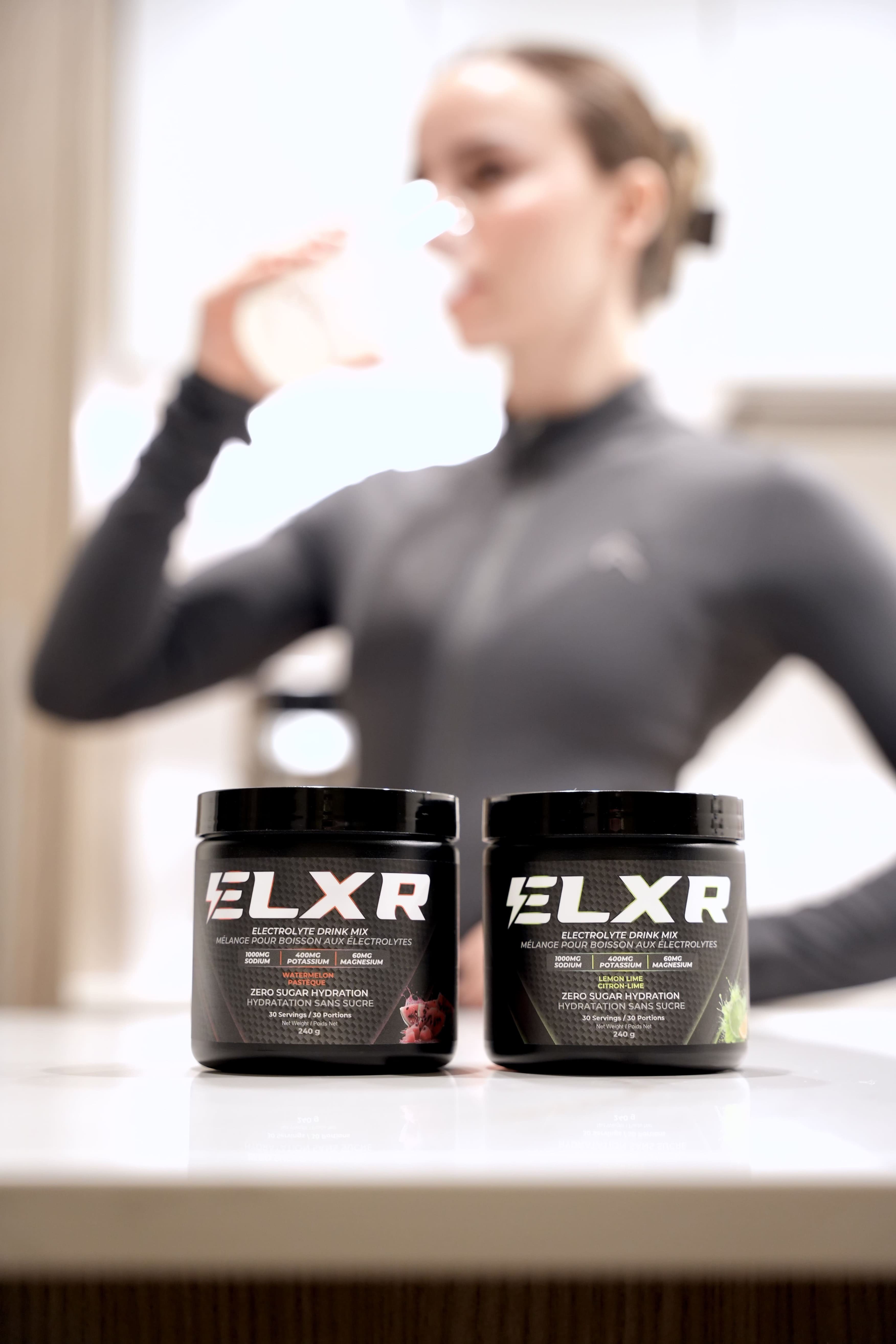 Two ELXR electrolytes containers on a surface with a blurred person in the background