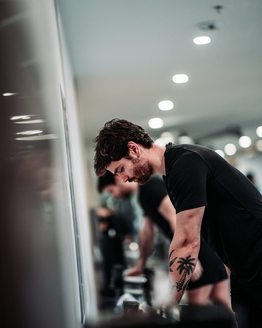 Man with a tattoo lifting weights in a gym.
