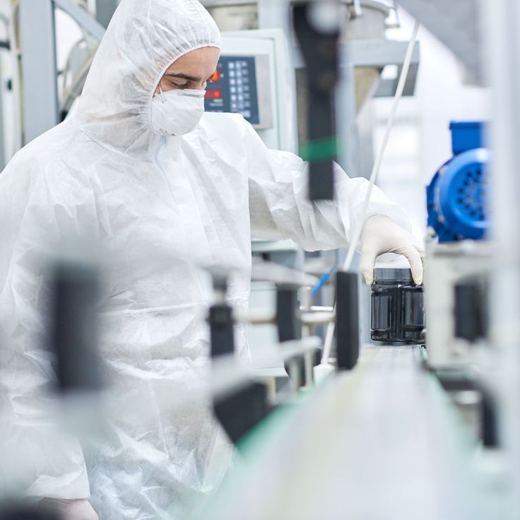Person in a white protective suit working in a factory setting
